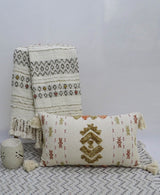 Colorful embroidered throw pillow with tassels displayed on beige furnishings