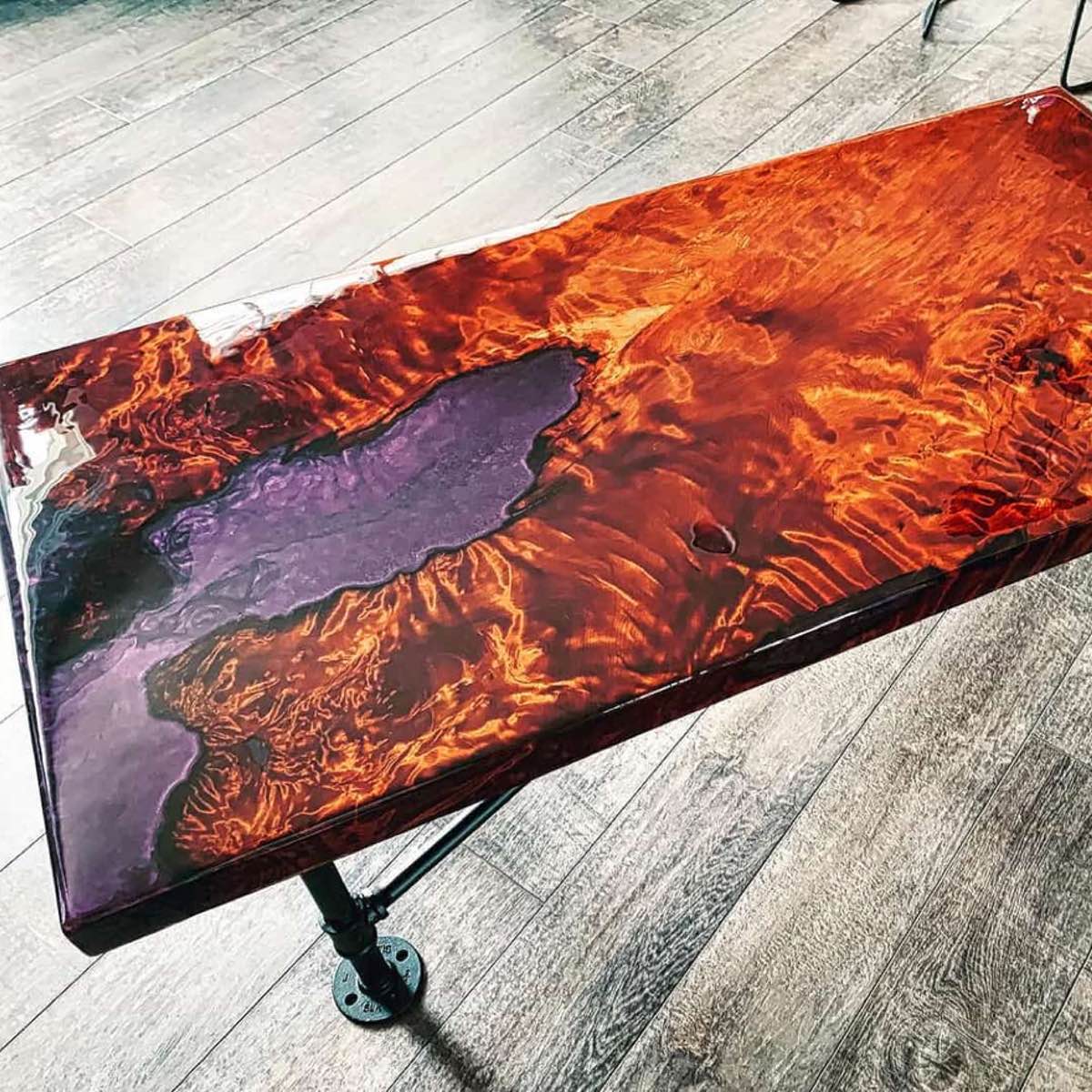 Table with a unique design featuring red and purple colors on a wooden floor.