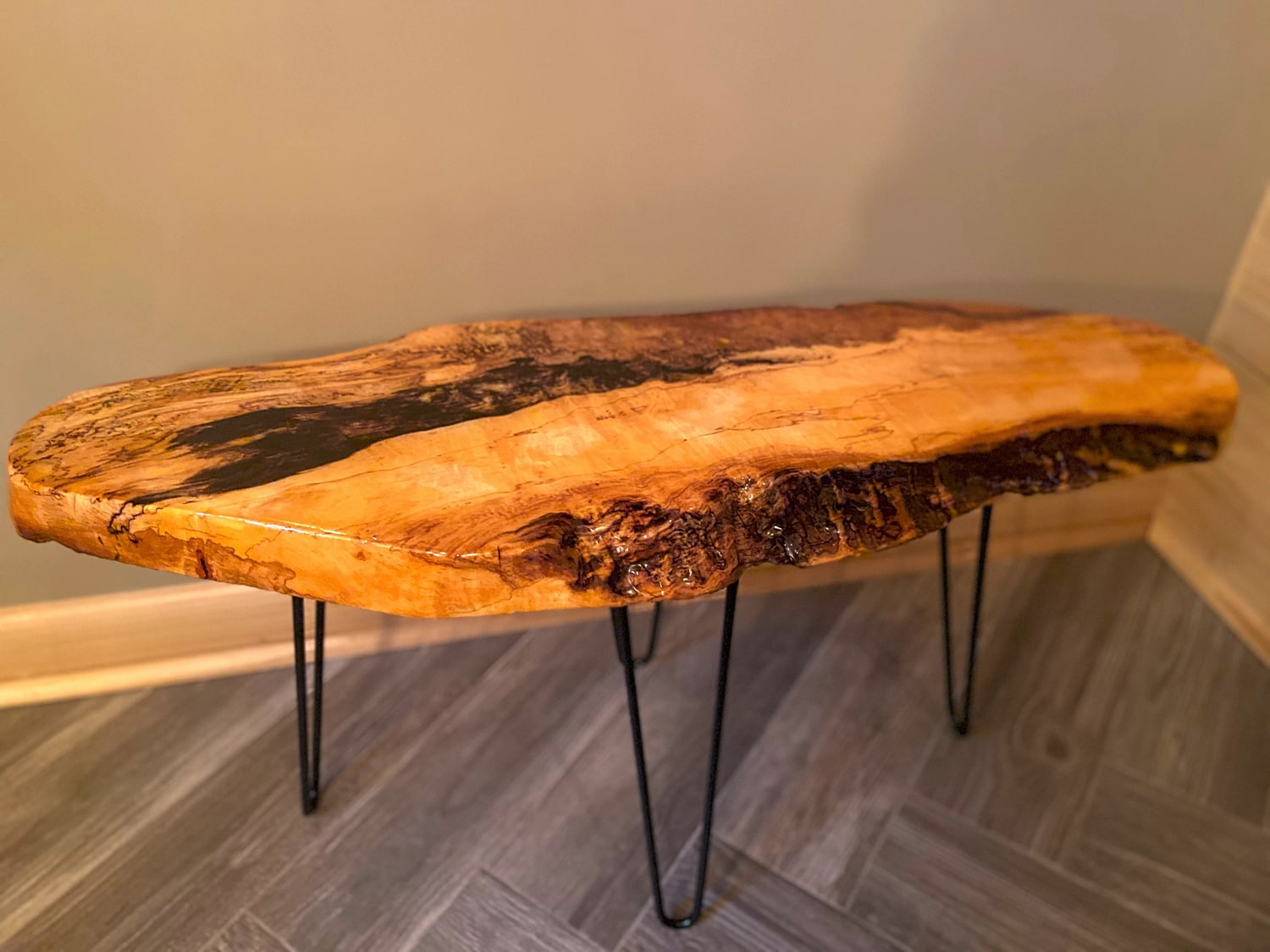Wooden coffee table with a natural edge design on a gray floor.