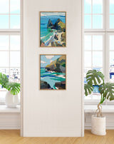 Two framed abstract coastal paintings featuring blue and green ocean waves and rocky cliffs, hung vertically on a white wall between tall windows with green potted plants nearby.