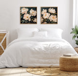 Two framed floral paintings with creamy white flowers and dark green leaves hang above a bed with white bedding in a bright, minimalist bedroom.