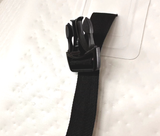 Close-up of a black plastic side-release buckle attached to a black woven strap resting on a light-textured surface.