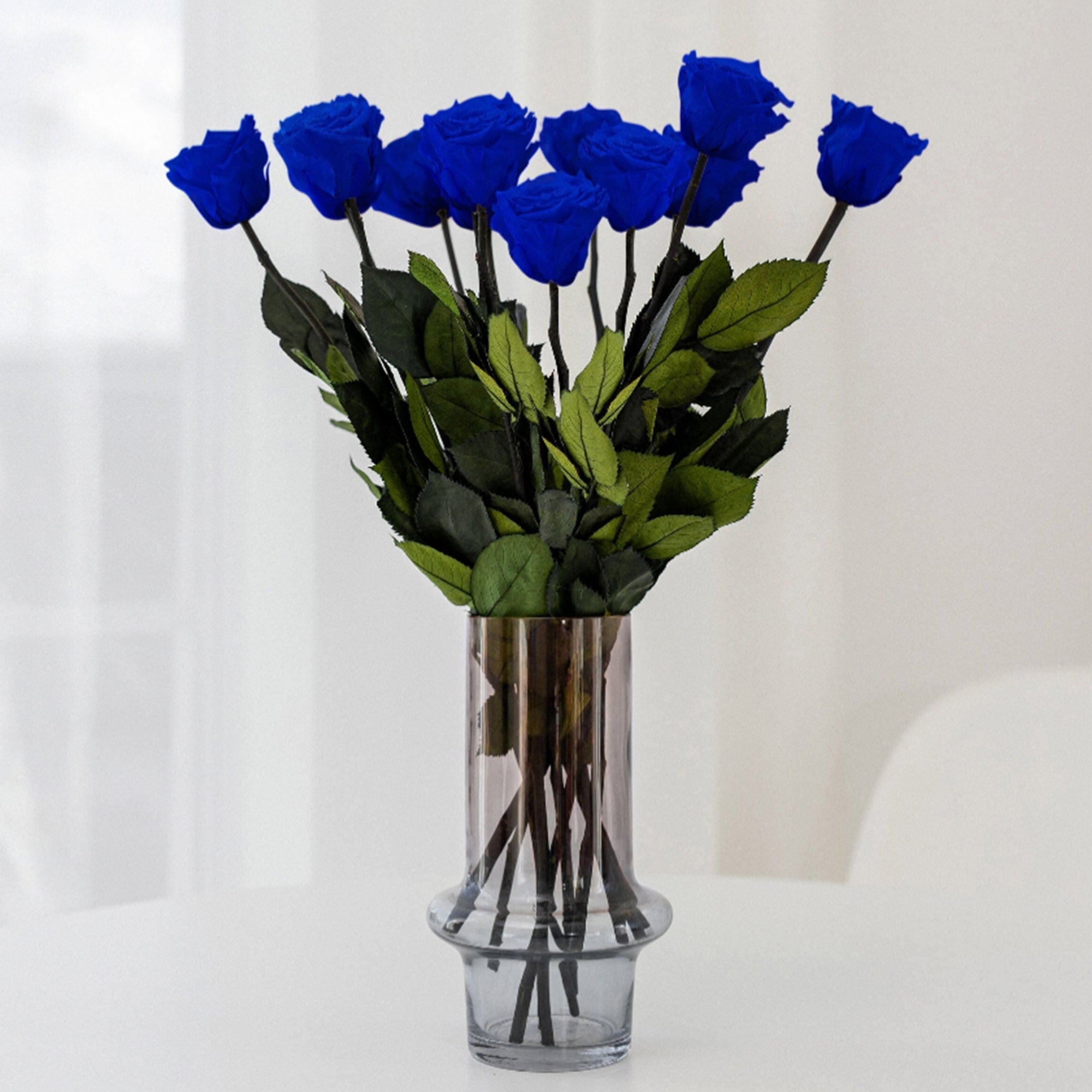 A dozen long stem preserved royal blue roses standing upright unarranged