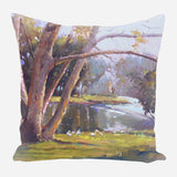 Pillow featuring an impressionistic landscape of tall trees with textured bark beside a sunlit riverbank with ducks in soft green, brown, and purple hues.