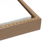Close-up of a wooden picture frame corner with a textured beaded inner edge, holding a white canvas stretched tightly over a wooden frame.