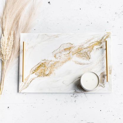 Marble-patterned Acrylic Resin Serving Tray with gold accents on a white surface with a candle and dried plants.