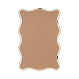Back of a scallop-edged rectangular mirror frame with a light beige finish and metal clips securing the backing board.