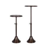 Two dark bronze metal adjustable drink tables with round tops and flared bases, shown side by side at different heights on a white background.