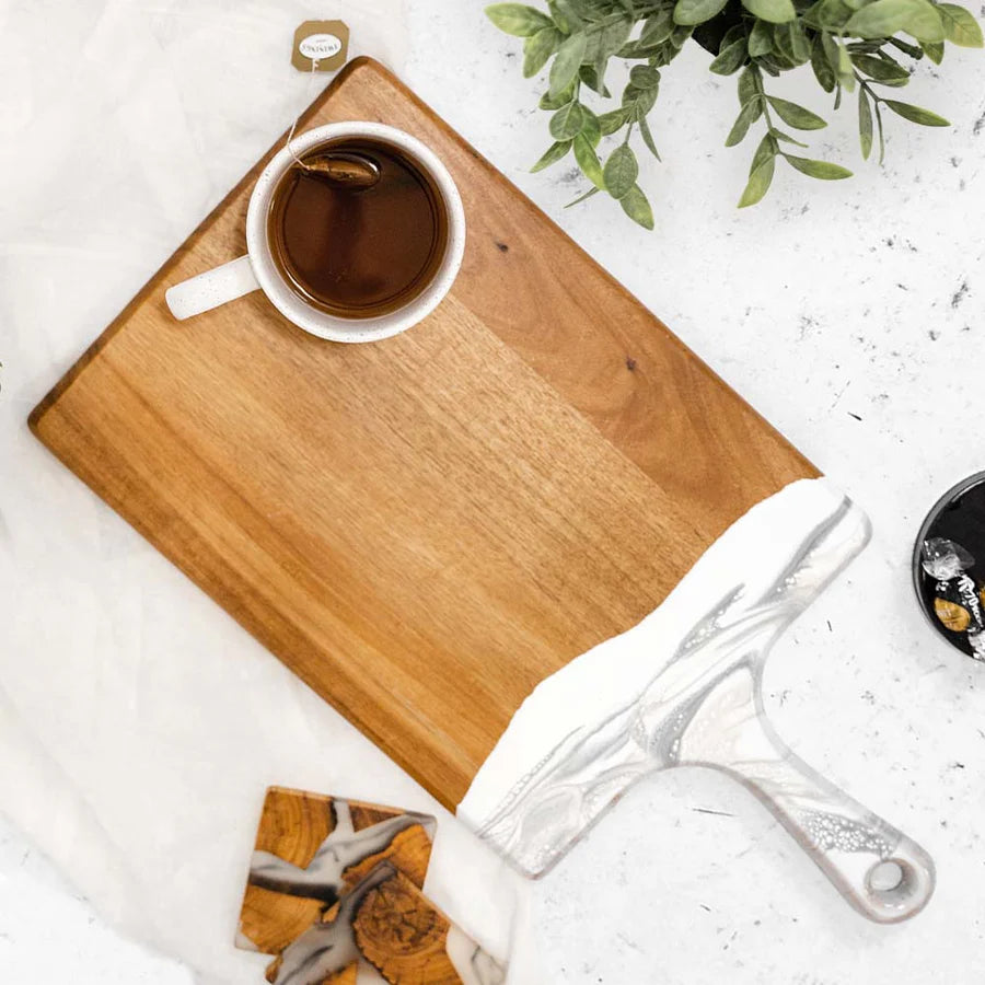 Cup of coffee on a resin charcuterie board with a plant in the background