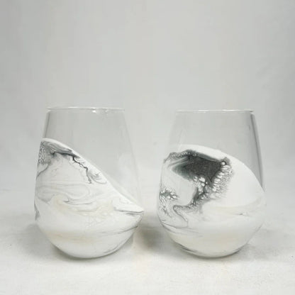 Two white resin wine glasses with silver marbled patterns on a light gray background