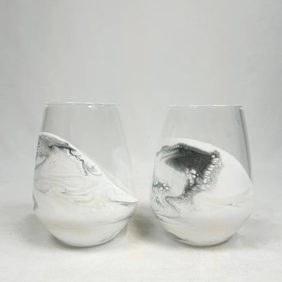 Two white resin wine glasses with silver marbled patterns on a light gray background