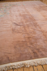 Vintage Japanese Art Deco carpet in muted pink with faint floral patterns in one corner and white fringes on hardwood floor.