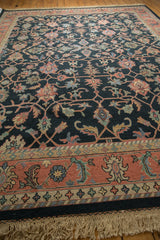 Vintage Serapi rug with a dark background, featuring intricate floral motifs in muted reds and greens and a wide terracotta border with symmetrical floral patterns.