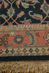 Section of a 9x12 vintage Serapi Indian Soumac design carpet featuring intricate floral and geometric patterns in muted blues, reds, and greens with fringed edges.