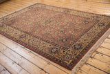 Rectangular vintage Romanian Tabriz design carpet with intricate floral motifs in rust, navy, and beige tones on wood plank floor, featuring fringed edges on two sides.