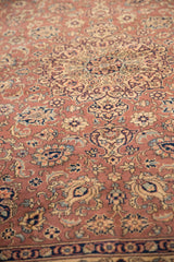 Vintage Romanian Tabriz carpet with intricate floral and medallion patterns in soft pink, beige, and navy tones, photographed from a slight angle.