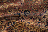 Close-up of a vintage Romanian Tabriz design carpet showing intricate floral and geometric patterns in warm brown, navy, and beige tones with visible folds.