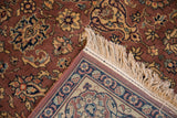 Corner of a vintage Romanian Tabriz design carpet with intricate floral patterns in beige, blue, and rust tones and a cream-colored fringe.