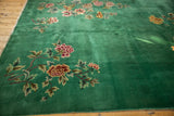 Green vintage Art Deco carpet featuring floral motifs in pink, yellow, and cream tones with leafy green accents on a wooden floor.