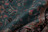 Close-up of folded vintage Indian Mohajeran Sarouk carpet with teal background, floral motifs, and red and beige accents in intricate patterns.