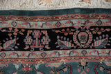 Section of a vintage Indian Mohajeran Sarouk carpet with floral motifs in muted reds, greens, and blues on a black background with a light blue border.