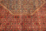 Close-up of a vintage Indian Bijar carpet with intricate floral and geometric patterns in red, orange, and blue hues featuring a central hexagonal medallion.