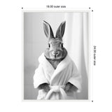 Black and white photo of a rabbit dressed in a white bathrobe, standing against a light, softly blurred background, facing forward with ears upright.