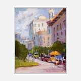 Impressionistic painting of a downtown street in midday light, featuring pastel-toned buildings, green trees, parked cars, and a bright street vendor cart with an orange umbrella.