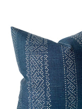 Close-up of a dark indigo pillow cover featuring vertical rows of small white dotted geometric patterns on textured fabric.