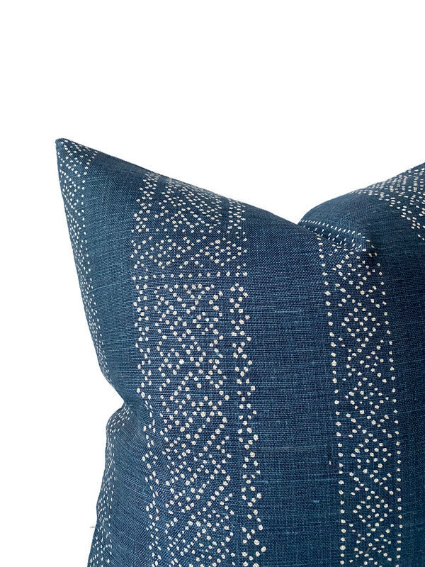 Close-up of a dark indigo pillow cover featuring vertical rows of small white dotted geometric patterns on textured fabric.