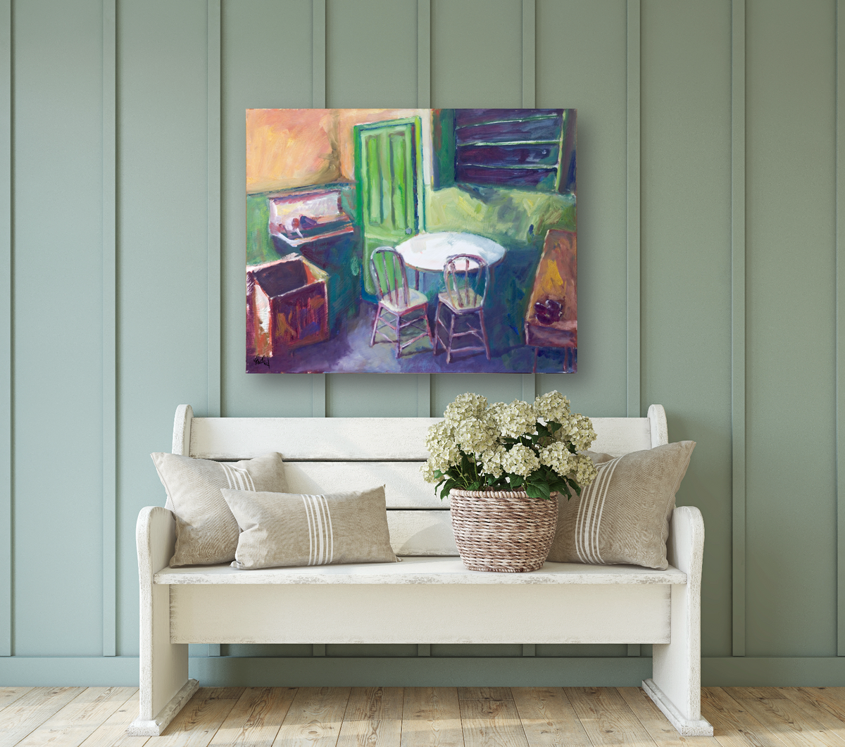 Colorful painting of an interior dining scene with a green door, round white table, two chairs, and a wooden box on a purple floor, displayed above a white bench.