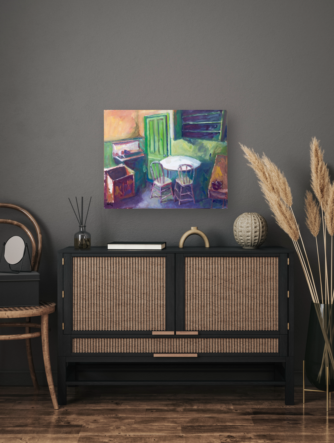 Colorful canvas painting depicting an interior with a green door, round table, chairs, and vibrant brushstrokes, hung above a black cabinet with woven panels.