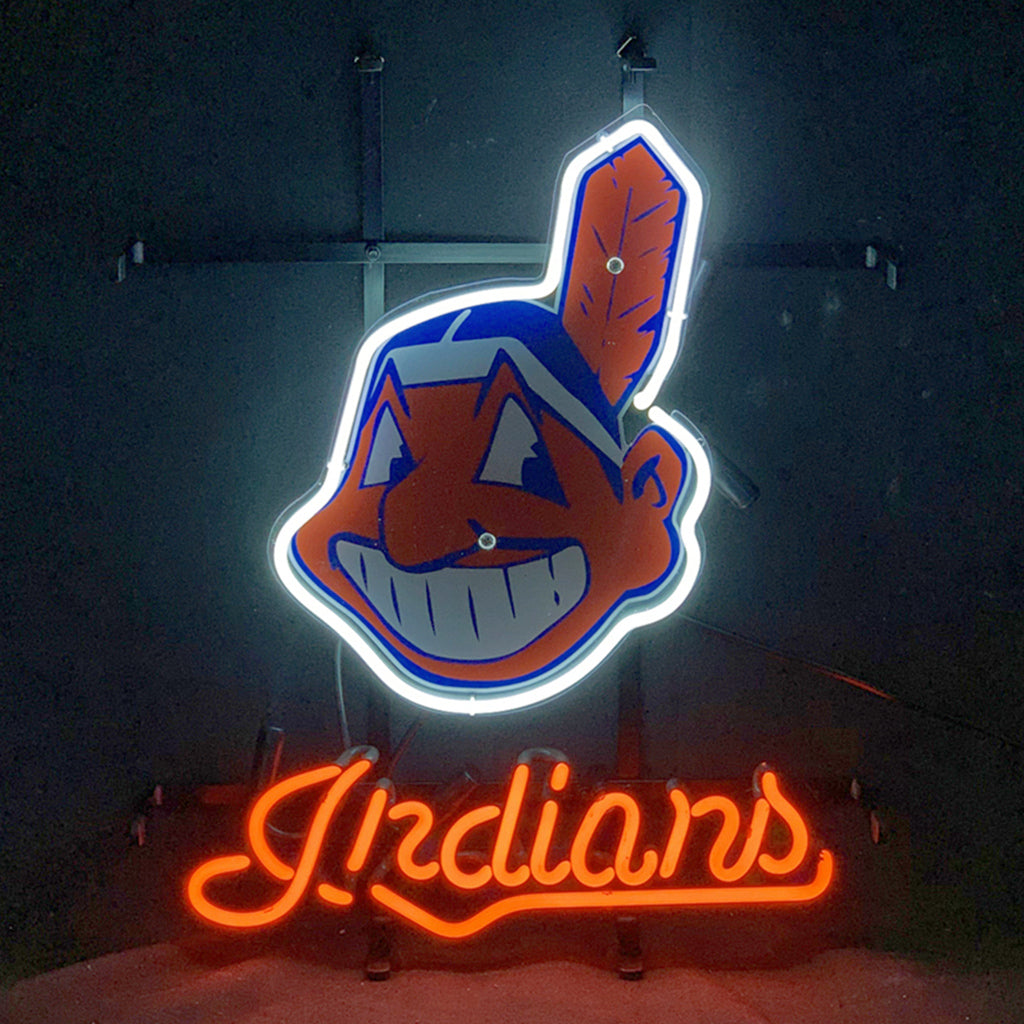 Neon sign with a glowing white outline of a cartoonish Native American head with a red feather and a wide grin above bright red cursive 'Indians' text on a black background.
