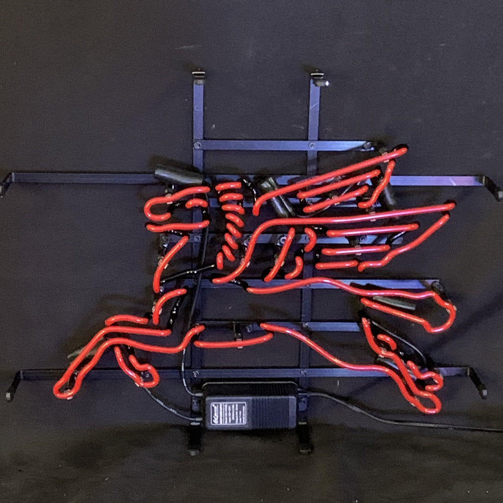 Red neon tubing shaped into a stylized flying horse mounted on a black metal frame with visible support bars, against a dark background.