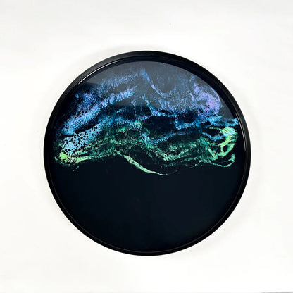 Round decorative resin tray with abstract blue and green design on a white background