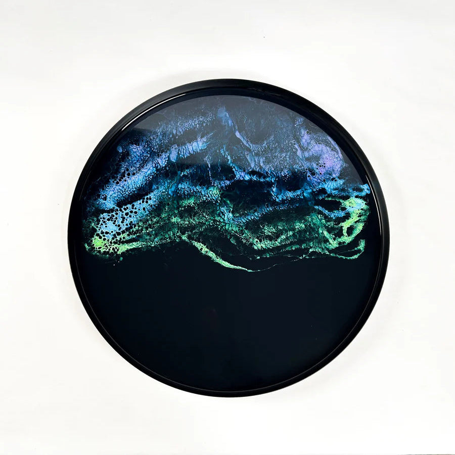 Round decorative resin tray with abstract blue and green design on a white background