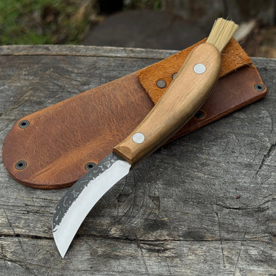 Mushroom knife with carbon steel blade, ash wood handle, built-in brush, and leather sheath for forest foraging