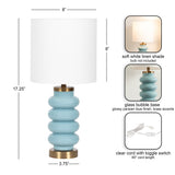 Table lamp with a glossy Parisian blue glass bubble base and a soft white linen drum shade, featuring brass accents and an 85-inch clear cord with toggle switch.