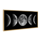 Framed canvas showing five detailed black-and-white moon phases from crescent to full, arranged horizontally on a black background with a light wood frame.