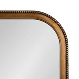 Close-up of an arched wall mirror corner featuring a smooth gold frame with a decorative row of bronze-colored beads along the edge
