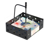 Square black metal napkin holder with star-shaped cutouts and a silver football-shaped napkin weight at the center holding colorful patterned napkins.