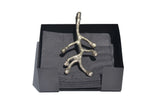 Silver metallic branch-shaped napkin holder on a black square base holding dark gray napkins, shown against a white background.