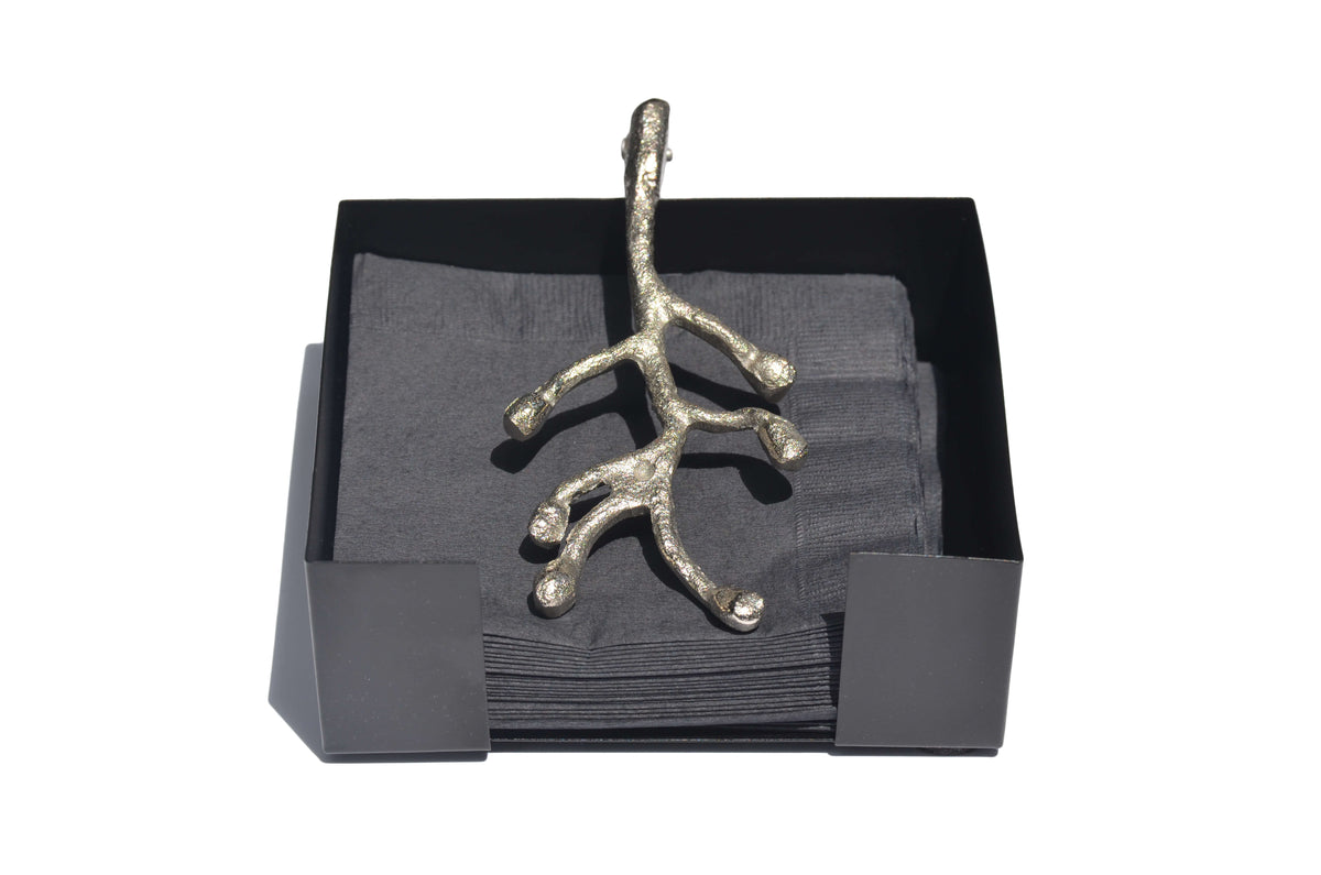 Silver metallic branch-shaped napkin holder on a black square base holding dark gray napkins, shown against a white background.