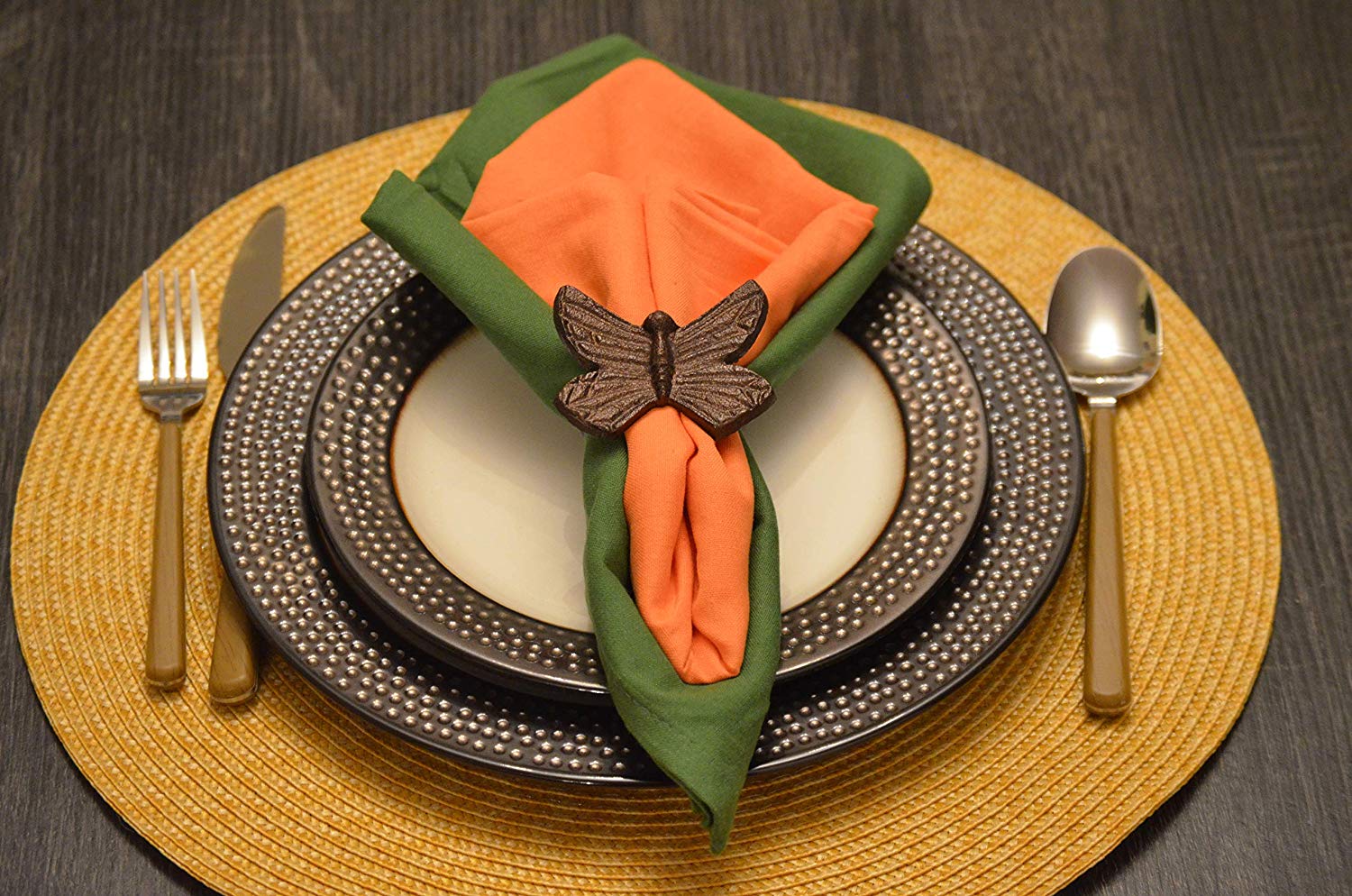 Set of four butterfly antique finish napkin rings in copper color arranged on a white surface