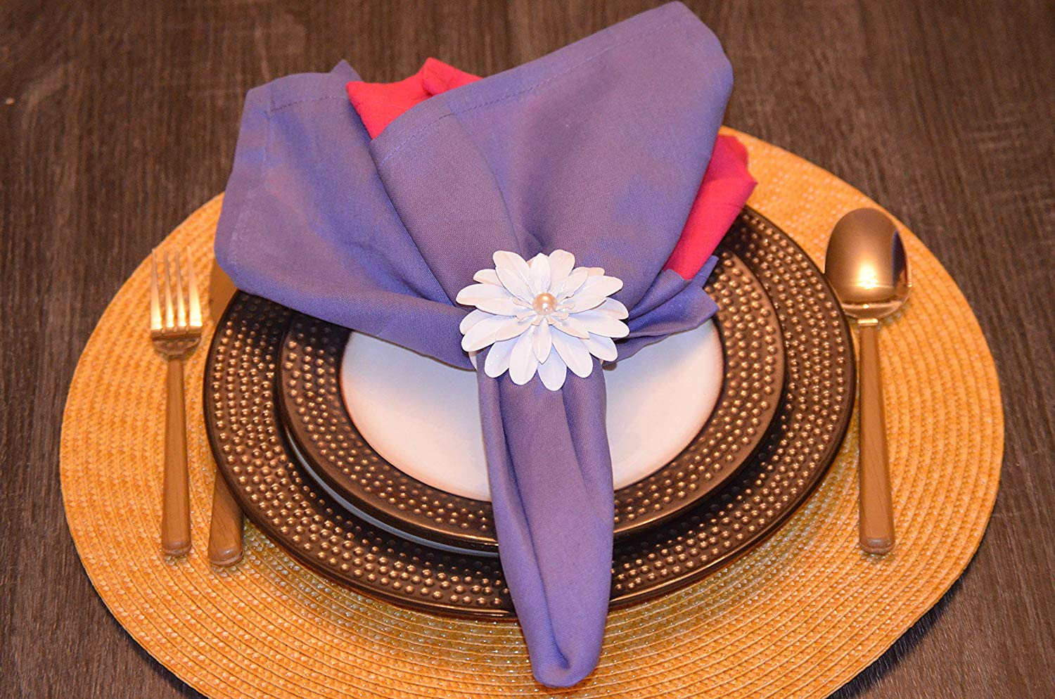 Set of four white floral napkin rings with pearl accents displayed on a dining table.