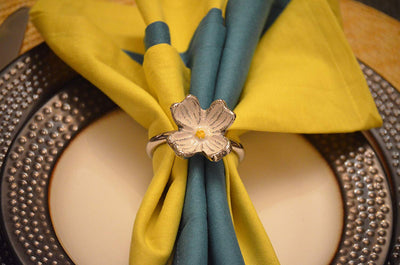 Set of four silver floral napkin rings with hand-painted yellow flowers on a fabric napkin