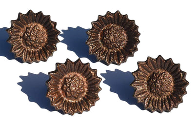 Four antique finish sunflower napkin rings arranged on a neutral cloth and tabletop