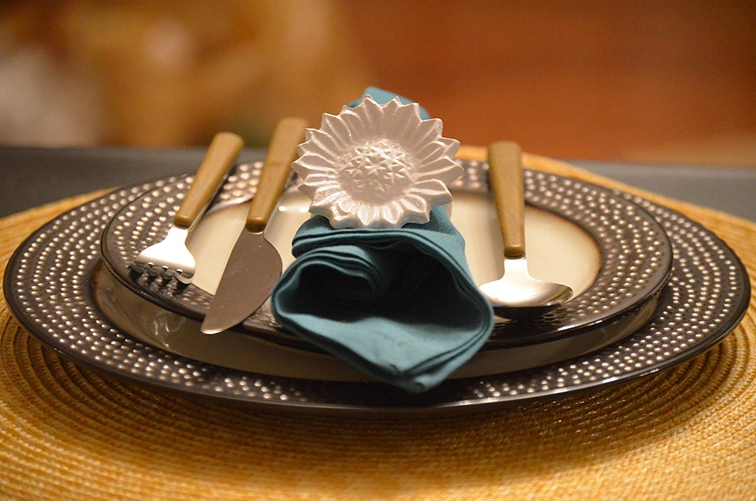 Four white sunflower-shaped napkin rings arranged on a dark wooden surface