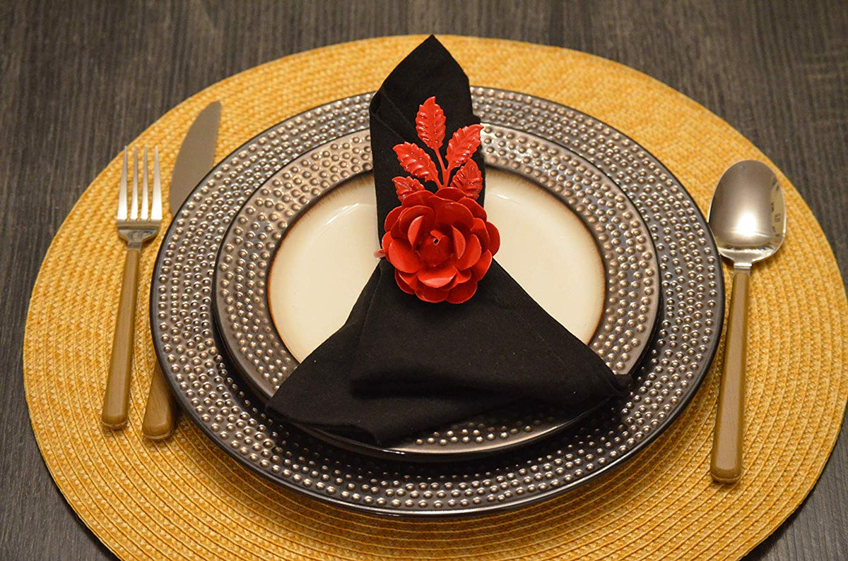 Set of four red rose napkin rings arranged on a dark wood surface.