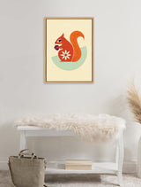 Framed stylized orange squirrel illustration with white flower pattern and green background shape, hanging above white bench with fur throw and beige bag on floor.